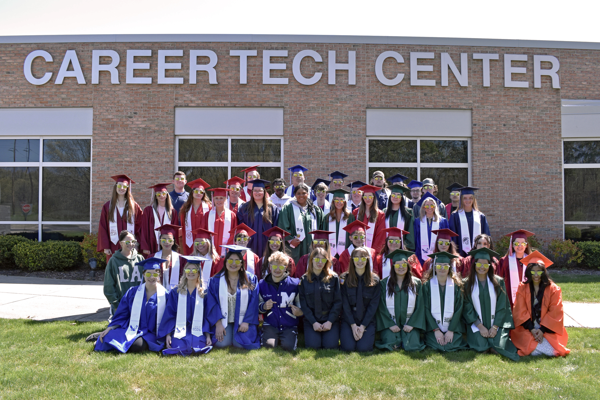 A group of students in graduation caps and gowns in a variety of colors