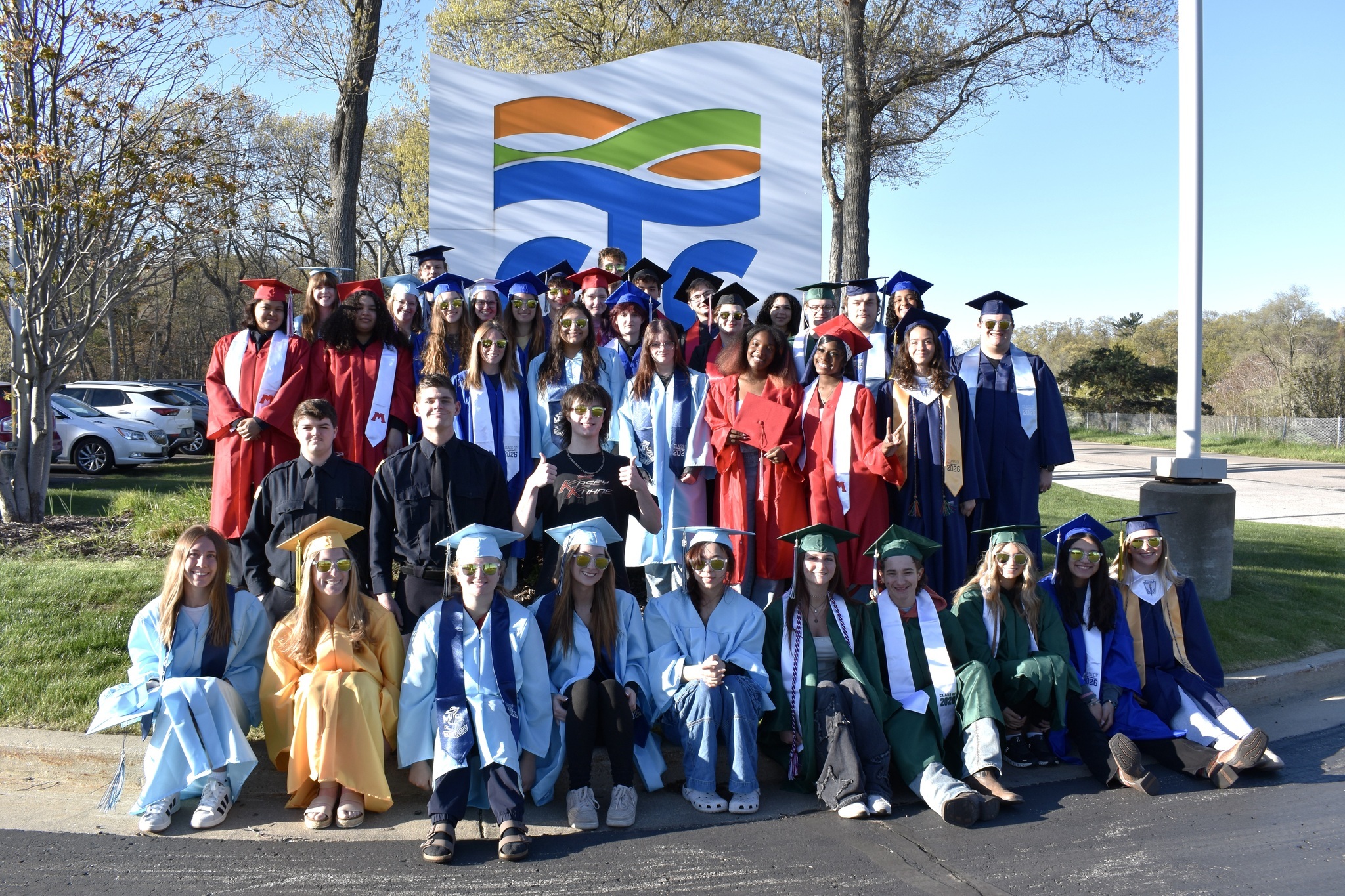 A large group of students in graduation caps and gowns in a variety of colors